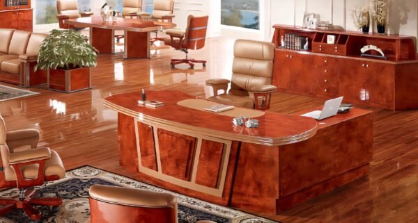 A grand, glossy reddish-brown wooden executive desk with a curved, ornate design and lighter wood accents, positioned on a shiny wooden floor in a luxurious office setting.